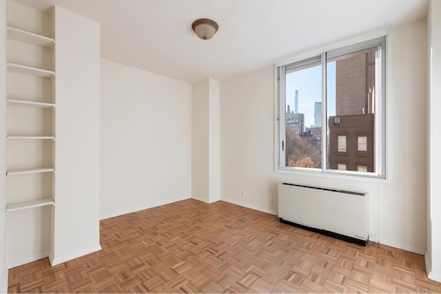 spare room featuring plenty of natural light, radiator, and light parquet flooring