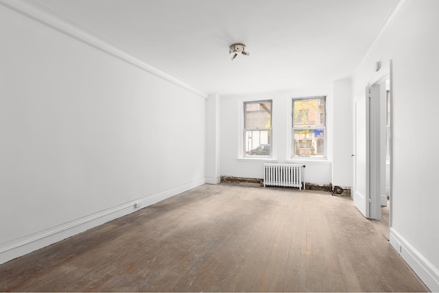 unfurnished room with radiator heating unit, baseboards, and wood-type flooring