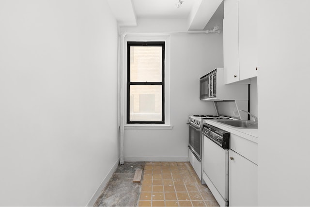 kitchen featuring stainless steel microwave, white cabinets, white dishwasher, a sink, and baseboards