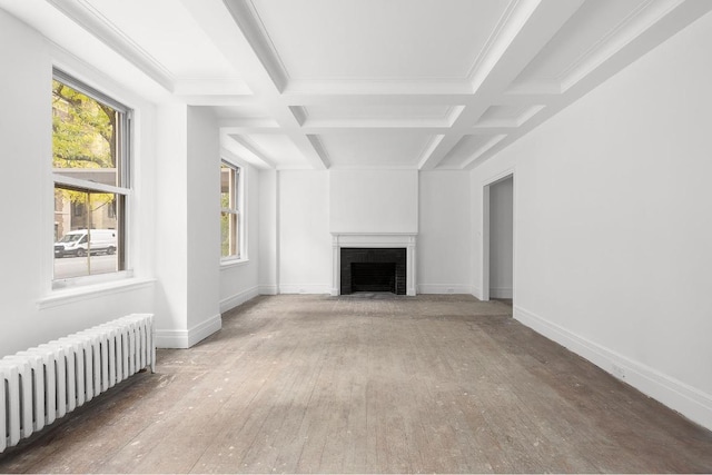 unfurnished living room with radiator heating unit, coffered ceiling, a fireplace, wood-type flooring, and beamed ceiling