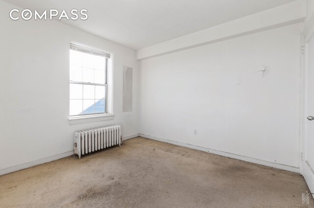 carpeted spare room featuring radiator heating unit