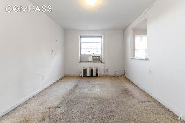 empty room with radiator heating unit, cooling unit, and a healthy amount of sunlight