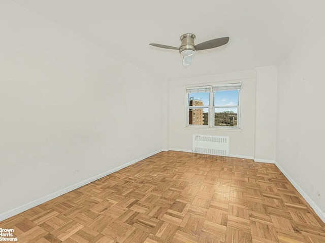 empty room with radiator heating unit, baseboards, and ceiling fan