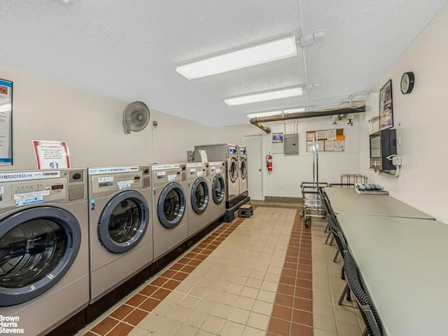 shared laundry area featuring a textured ceiling, tile patterned flooring, washing machine and dryer, and electric panel