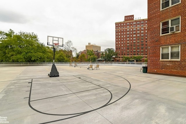 view of sport court featuring community basketball court, fence, and a city view