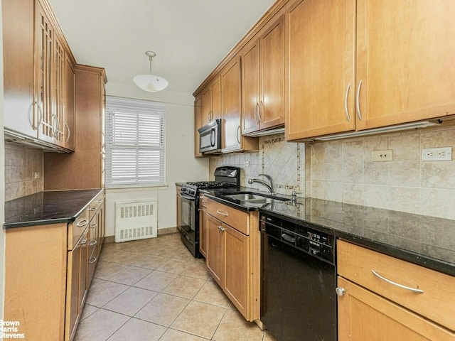 kitchen featuring brown cabinets, radiator, a sink, dark stone counters, and black appliances