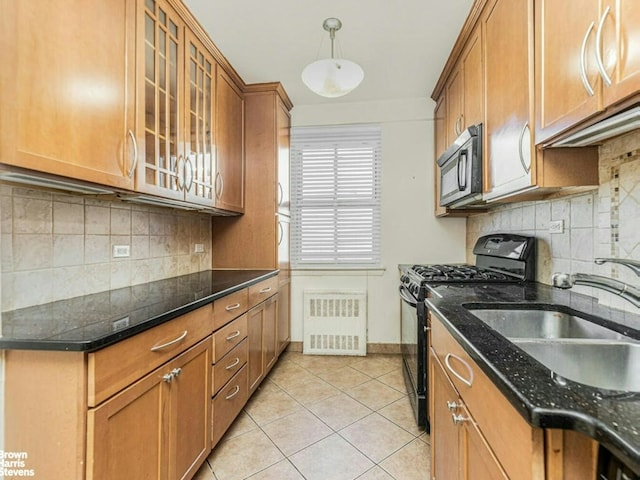 kitchen featuring pendant lighting, glass insert cabinets, brown cabinetry, a sink, and black appliances