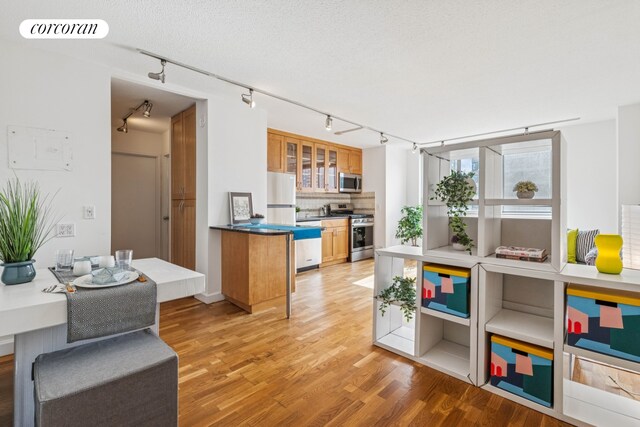 kitchen with stainless steel appliances, visible vents, light wood-style flooring, decorative backsplash, and brown cabinetry