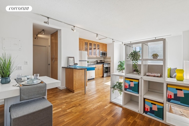 kitchen with visible vents, brown cabinetry, decorative backsplash, appliances with stainless steel finishes, and light wood-type flooring