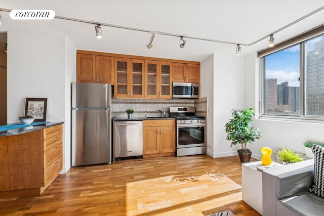 kitchen featuring stainless steel appliances, visible vents, light wood-style flooring, brown cabinetry, and a sink