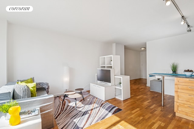 living room with light wood-type flooring, visible vents, baseboards, and rail lighting