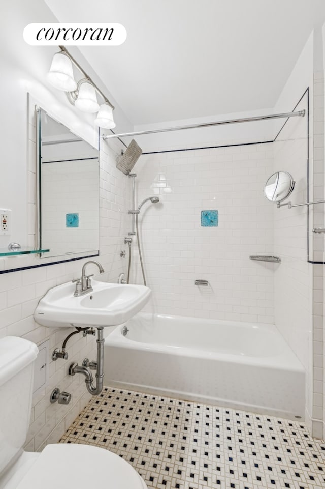 full bathroom featuring a sink, shower / bath combination, toilet, and tile walls