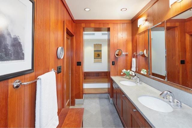 bathroom with a sink, wood walls, and double vanity