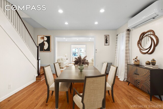 dining room featuring baseboards, stairway, an AC wall unit, recessed lighting, and light wood-style flooring