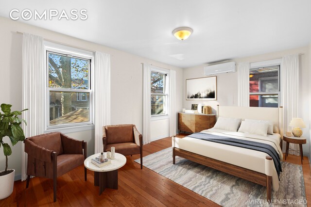 bedroom featuring an AC wall unit and wood finished floors
