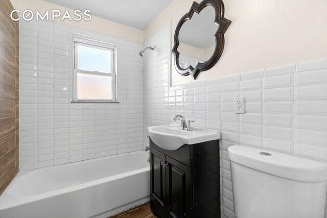 bathroom featuring toilet, tile walls, shower / tub combination, and vanity