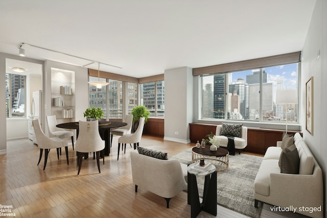 dining space featuring a view of city, baseboards, a wealth of natural light, and light wood-style floors