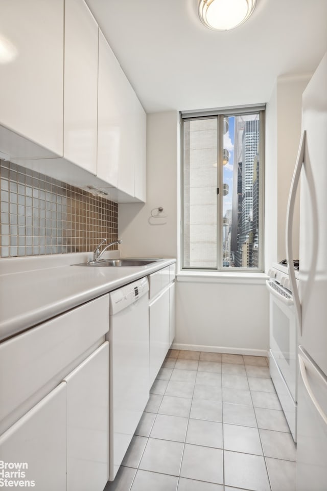 kitchen with light tile patterned floors, light countertops, white cabinetry, a sink, and white appliances