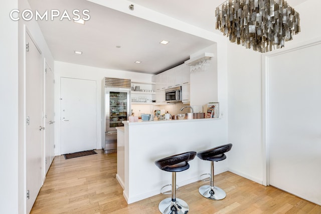 kitchen featuring white cabinets, appliances with stainless steel finishes, light wood-type flooring, and open shelves