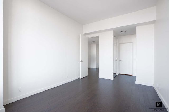 spare room with baseboards and dark wood finished floors