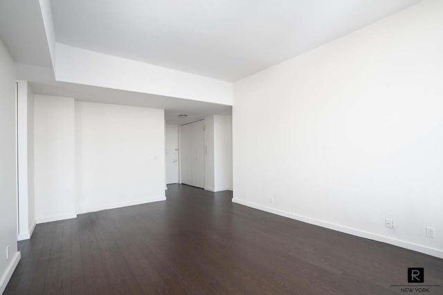 spare room with dark wood-type flooring and baseboards