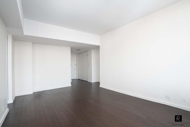spare room with baseboards and dark wood-style floors
