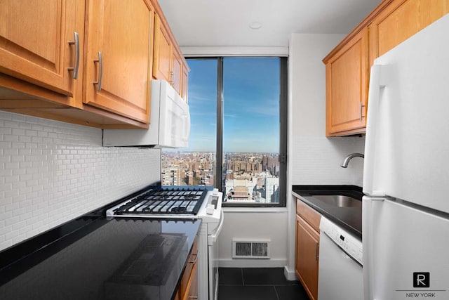 kitchen featuring white appliances, tasteful backsplash, visible vents, dark countertops, and a sink