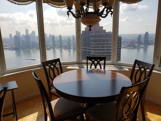 dining room with light parquet floors, a water view, and an inviting chandelier