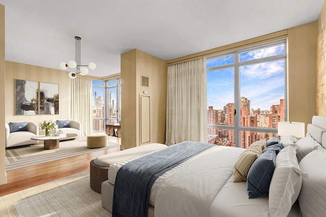 bedroom with a view of city, floor to ceiling windows, visible vents, and wood finished floors