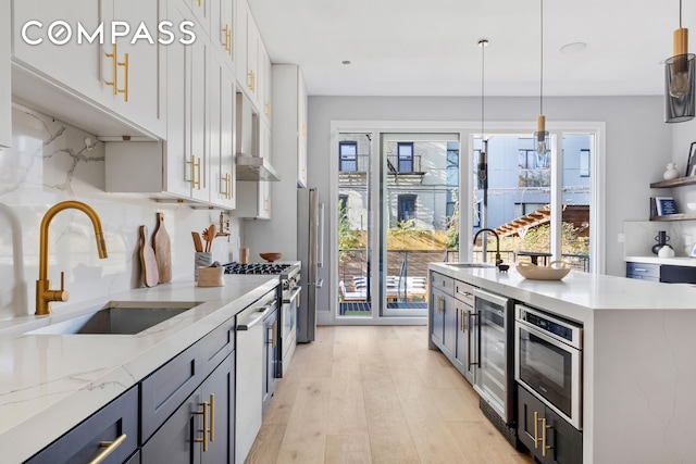 kitchen with beverage cooler, white cabinets, light wood-style floors, and a sink