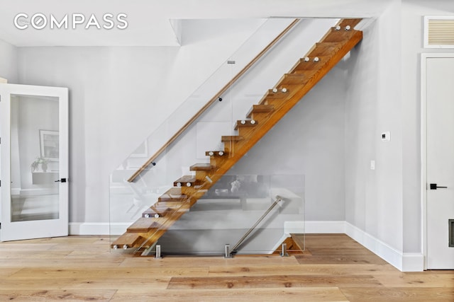 stairs featuring visible vents, baseboards, and wood finished floors