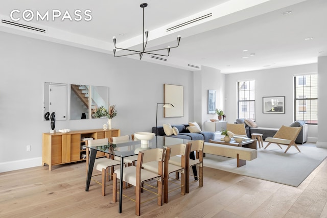 dining room featuring a notable chandelier, visible vents, light wood-style flooring, and baseboards