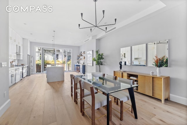 dining space with light wood-style floors, baseboards, and a chandelier