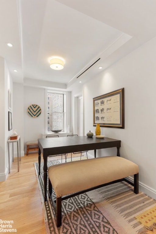 dining space with light hardwood / wood-style floors and a raised ceiling