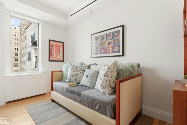 sitting room featuring light wood-type flooring and a tray ceiling