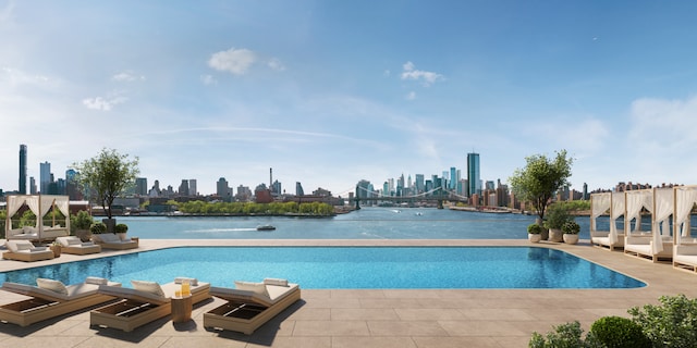 view of pool with a patio area, a water view, and a city view