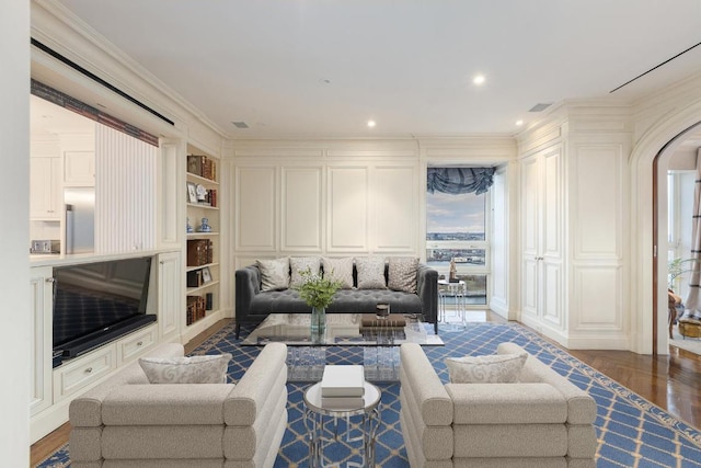 living room featuring built in shelves, ornamental molding, and hardwood / wood-style flooring