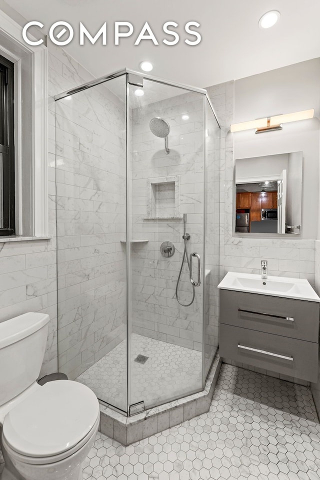full bath featuring tile walls, a stall shower, vanity, toilet, and recessed lighting