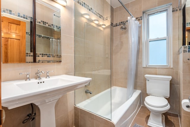 full bathroom with shower / tub combo with curtain, tile patterned floors, toilet, sink, and tile walls