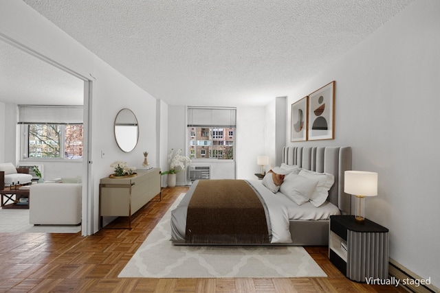 bedroom with parquet floors, a textured ceiling, and baseboard heating