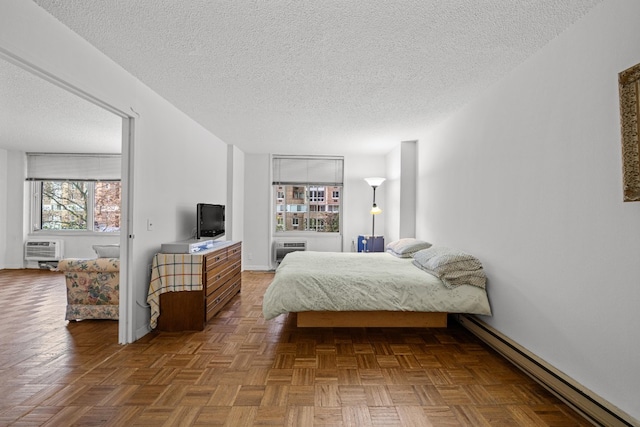 bedroom with a baseboard radiator, parquet flooring, a wall mounted air conditioner, and a textured ceiling