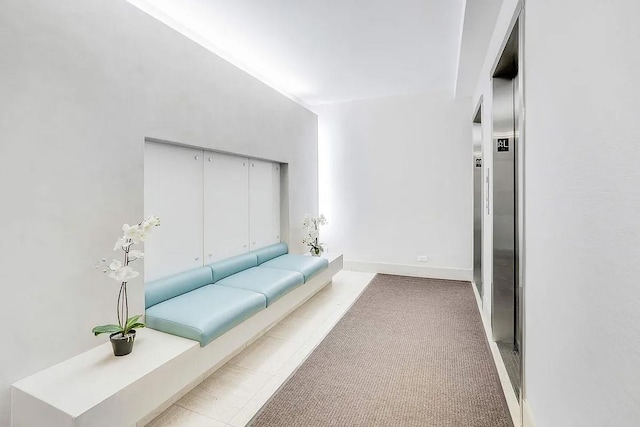 hallway with baseboards and light colored carpet