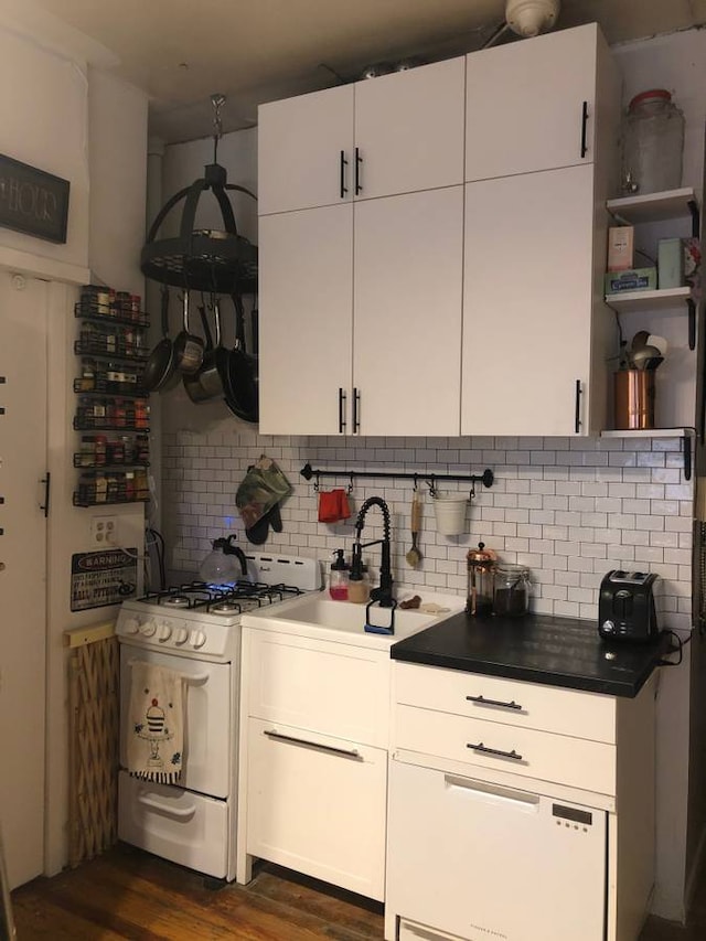kitchen with backsplash, dark wood finished floors, white gas range oven, white cabinets, and a sink
