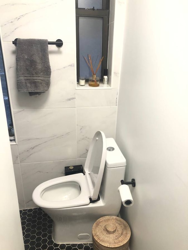 bathroom with tile walls and toilet