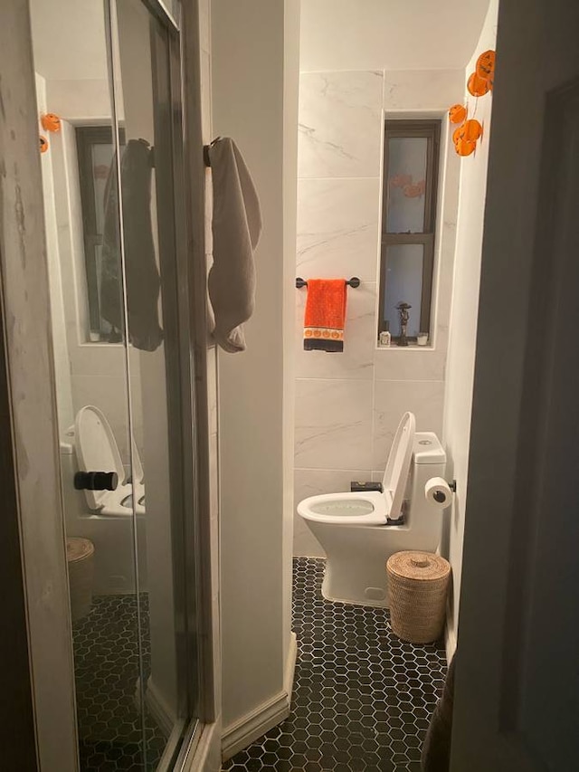 full bathroom with tile patterned flooring, tile walls, toilet, and a stall shower