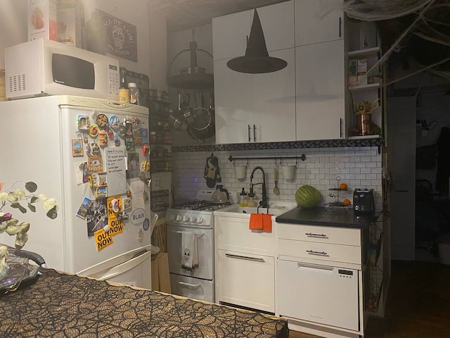 kitchen with white cabinetry, white appliances, dark countertops, and backsplash