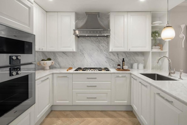 kitchen featuring sink, appliances with stainless steel finishes, light stone counters, white cabinets, and wall chimney exhaust hood