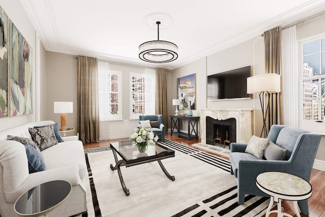 living room featuring hardwood / wood-style flooring, a wealth of natural light, ornamental molding, and a fireplace