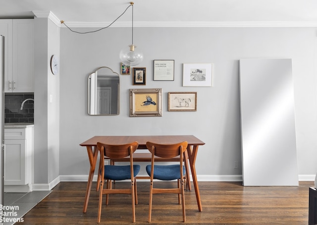 dining area with dark wood-type flooring, crown molding, and baseboards