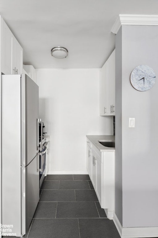 kitchen with fridge, stainless steel range oven, sink, and white cabinets